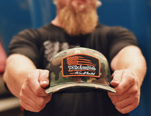 Load image into Gallery viewer, &quot;We The Essentials&quot;  - Camo Trucker Hat with Orange Patch
