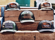 Load image into Gallery viewer, "We The Essentials" Camo Trucker Hat with Leather Patch