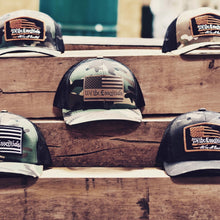 Load image into Gallery viewer, &quot;We The Essentials&quot; Multicam Green and Black Trucker Hat with Orange Patch
